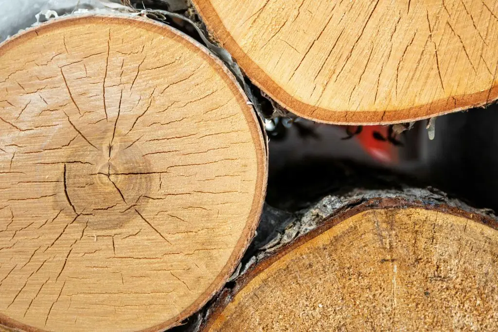 Feuerholz-Wellein: Detailaufnahme von Hartholzscheiten mit Baumrinde, bereit für Ihr Kaminfeuer.